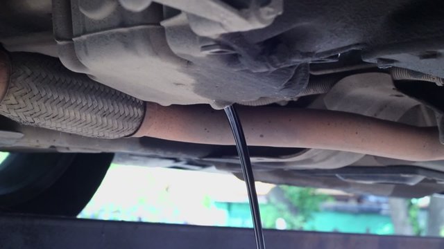 Oil pours out from car reservoir after man open cap, closeup