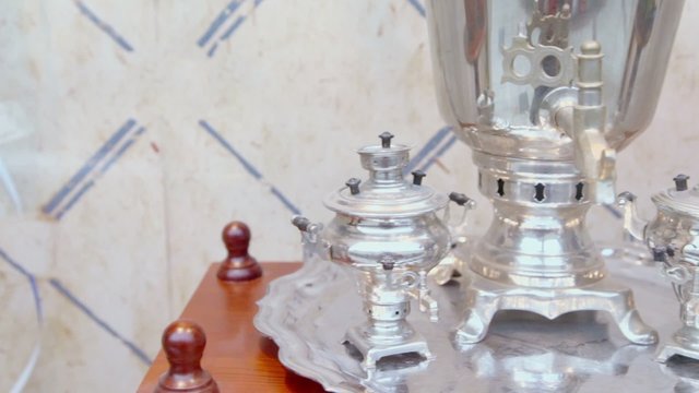 Three retro russian samovars on silver tray at wooden table