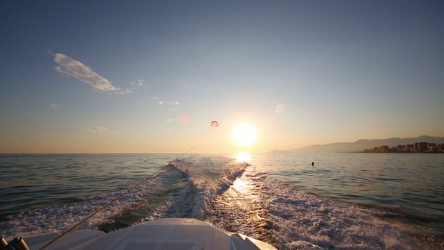 Glider flies over sea at evening and traces of boat on water