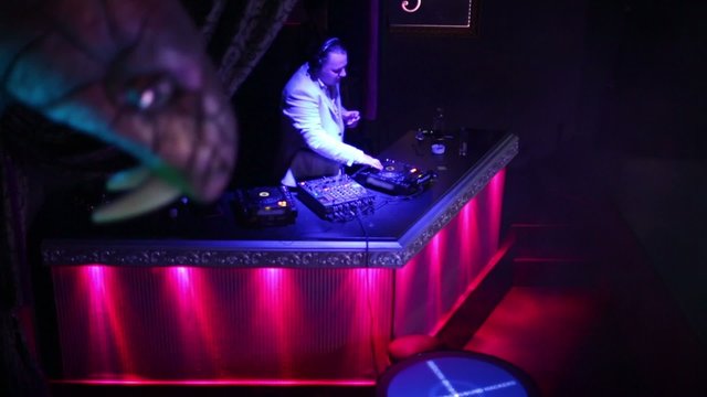 DJ works with musical equipment at his workplace in nightclub
