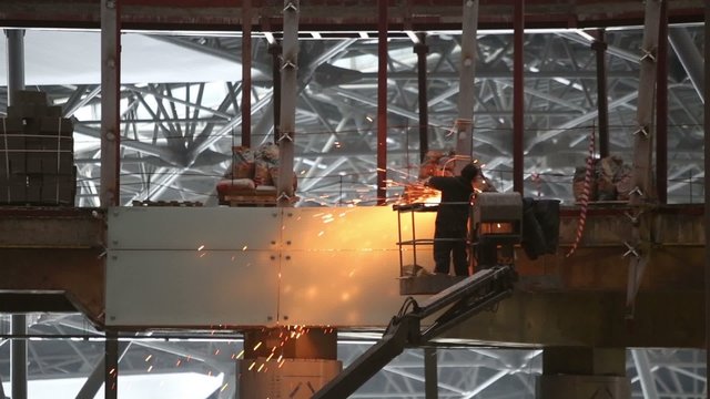 Worker cuts metal on construction of new modern building