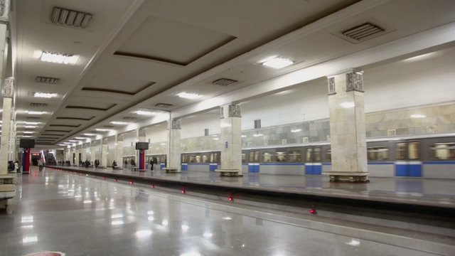 Two trains arrive at metro station with three lines, panoramic motion