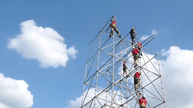 Team of climbers mounts tower against sky