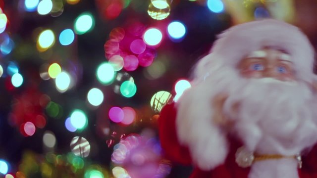 Toy Santa Claus dances and sing near garland of Christmas tree