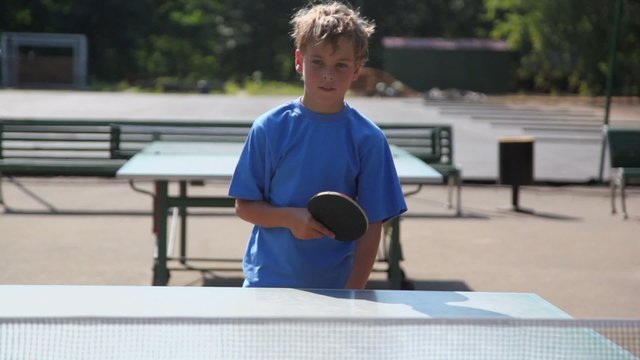 Boy in blue shirt plays ping pong and makes victorious strike