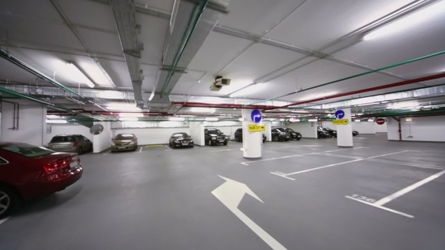 cars stand in underground parking with piping and illumination