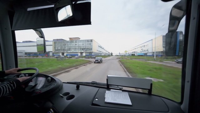 Bus rides by road among buildings of large factory