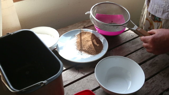 caucasian woman sifts malt powder through bolter with spoon