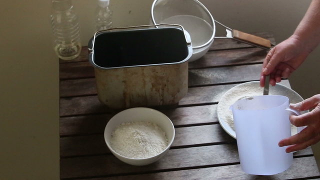caucasian woman puts flour with spoon into measuring cup	