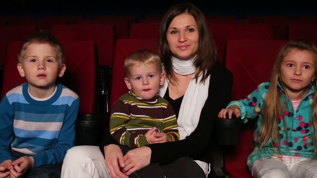 woman with her two sons and daughter are sitting in the cinema