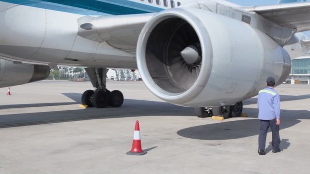 Worker checks turbine of aircraft which stands at airport field