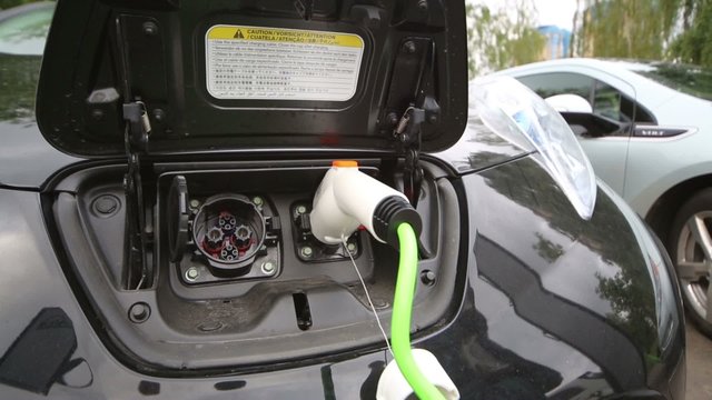 The man opens the lid for charging electromobile Nissan Leaf