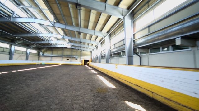 Empty indoor horse riding hangar with sandy covering