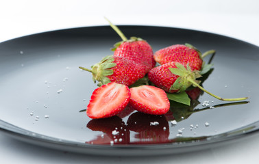 Fresh of half strawberry on black dish and reflex