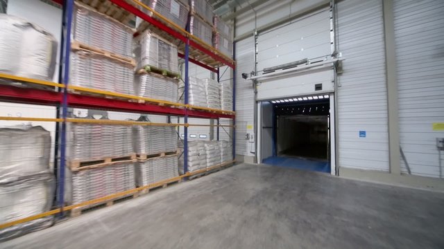 Goods lay on shelves in big warehouse with gates at factory