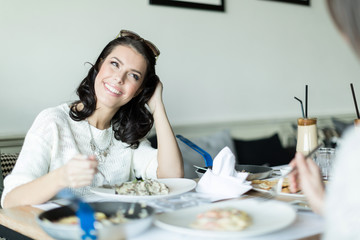 Two beautiful ladies eating and talking in a restaurant