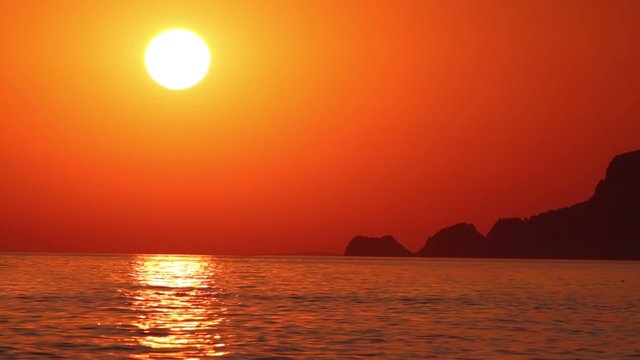 Seascape of red sunset at sea and mountains silhouette