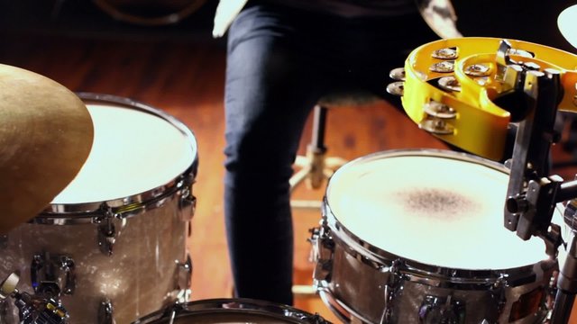 Young man beats drums by two wooden sticks