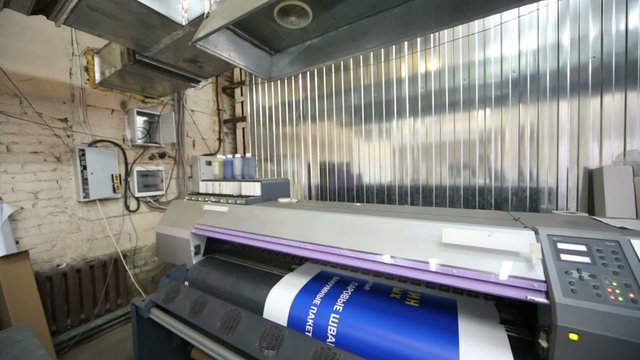 Plotter in printing house prints blue image on a large paper