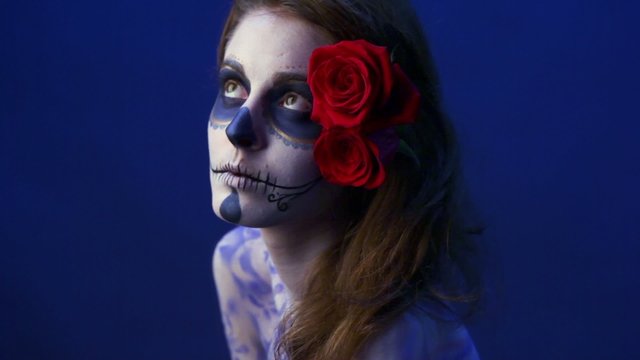 Model with rose in hair and angry make-up poses