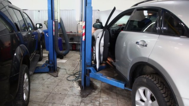 Two offroders stands on lifting machines at car service