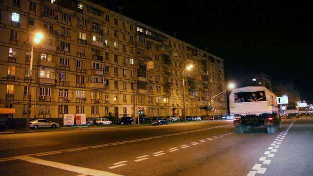 Military trucks with soldiers ride by street at night