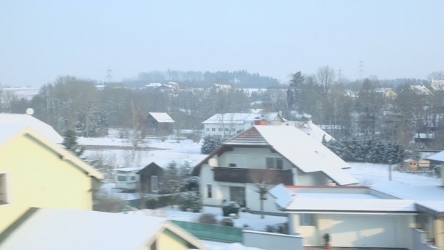 Many houses at village on winter day, view from train in motion