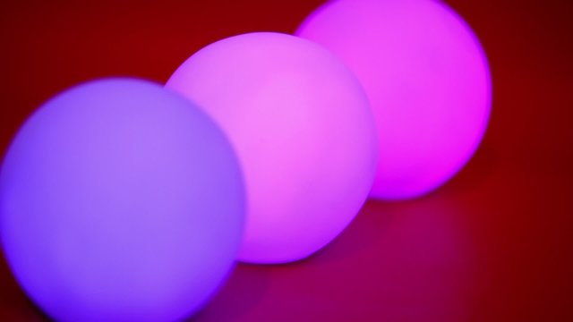 Three colorful spheres with glimmering light at red background