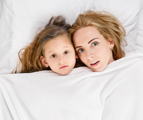 Mother playing with daughter on the bed