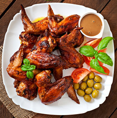 Plate of chicken wings on wooden background