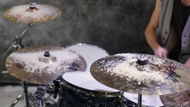 Drummer plays drums covered snow in gray room at studio