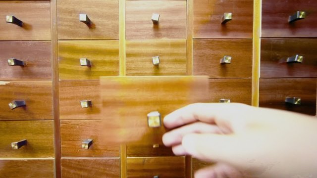 Hand opens box in cabinet and takes cd disk from it, then close