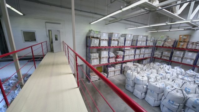 Man walks by bridge in warehouse at Caparol factory 