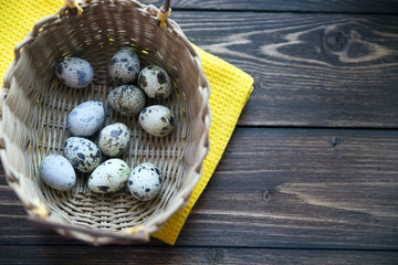 Easter quail eggs in the basket on rustic wooden background