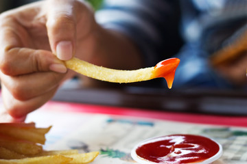French fries with ketchup in hand on table, soft focus
