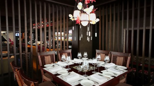 Dishes and glasses on table in empty restaurant with bar