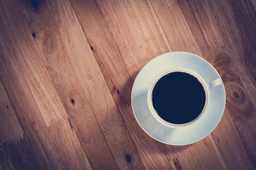 Coffee cup with black coffee on wooden table - vintage tone