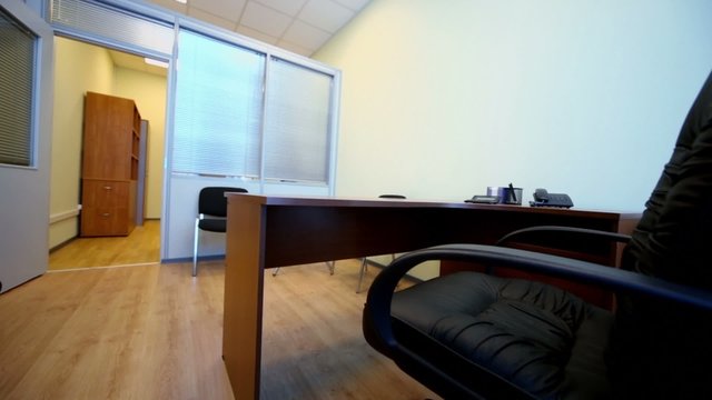 Interior of small empty office cabinet with black armchair