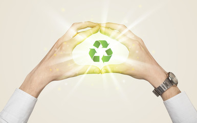 Hands creating a form with recycling sign