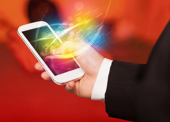 Hand holding smart phone with abstract glowing lines