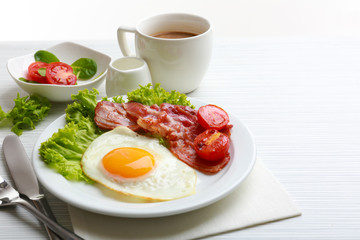 Bacon and eggs on color wooden table background