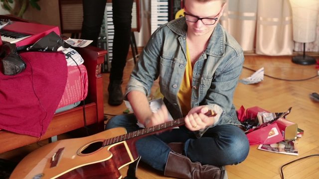 Young stylish man sitting on the floor and break guitar