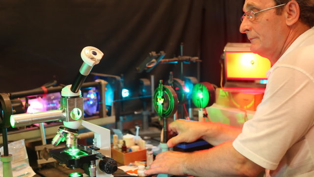 scientist adjusts device consisting of laser, microscope and enlargers close up