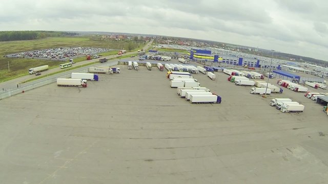Big parking lot with many trucks near road, above view