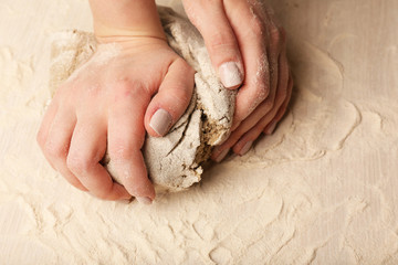Making dough by female hands on wooden table background