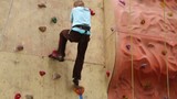 Boy descends down from steep wall at climbing gym hall