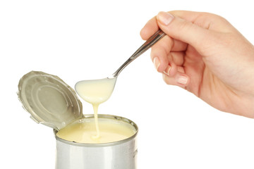 Tin can of condensed milk with spoon isolated on white