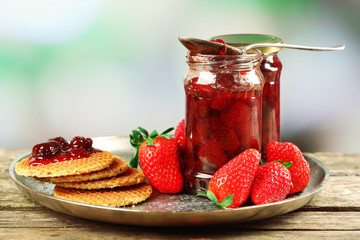 Jars of strawberry jam with berries and wafers