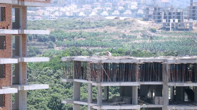 Builders work at top floor of new building in afternoon, time lapse