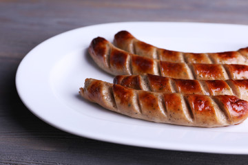 Grilled sausages on plate on table close up